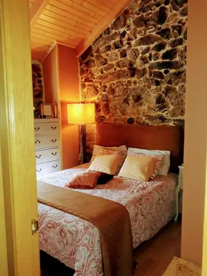 a bedroom with a bed with a stone wall at Casa Rural Cabo de Aráns in Oroso