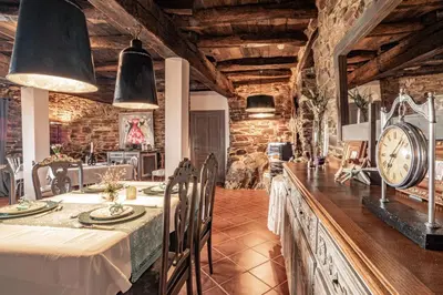 a dining room with a table and a clock at Complejo Rural Lar de Vies in A Pontenova