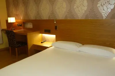 a bedroom with a bed and a desk with a chair at Hotel Nordés in Burela de Cabo