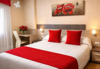a bedroom with a large bed with red pillows at Hotel Spa Galatea in Burela de Cabo