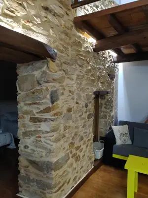 a stone wall in a room with a blue couch at Casa das Pozas in Distriz