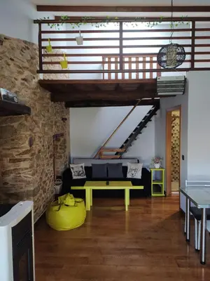 a living room with a yellow bench and a stone wall at Casa das Pozas in Distriz