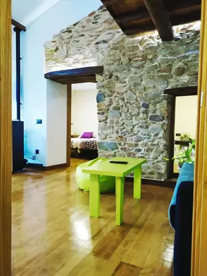 a green table in a room with a stone wall at Casa das Pozas in Distriz