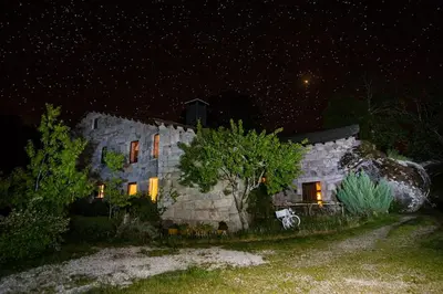 a large stone building with lights on at night at A Aira da Petada Hotel Boutique in Corzos