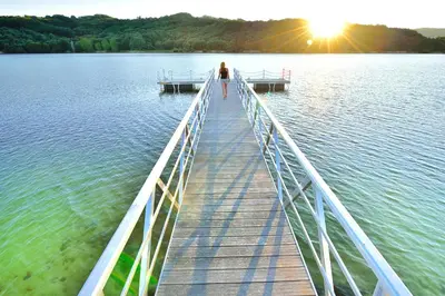 a woman walking on a wooden bridge over a lake at A Aira da Petada Hotel Boutique in Corzos