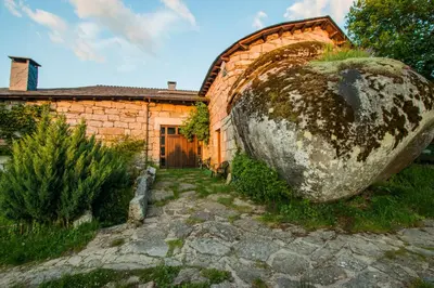 a large stone boulder sits outside of a brick building at A Aira da Petada Hotel Boutique in Corzos