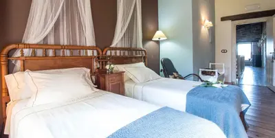 two beds in a hotel room with white sheets at A Aira da Petada Hotel Boutique in Corzos