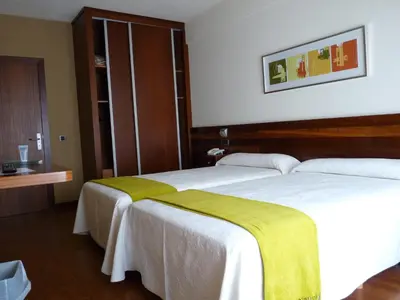 a hotel room with two beds with yellow blankets at Hotel Restaurante San Anton in Tapia de Casariego