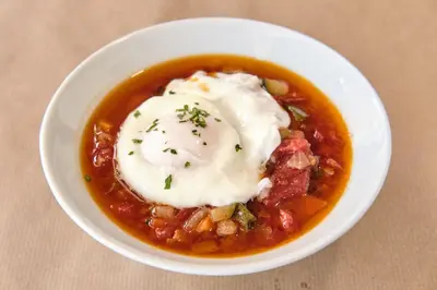 a bowl of chili with poached eggs on top at Hotel Restaurante San Anton in Tapia de Casariego