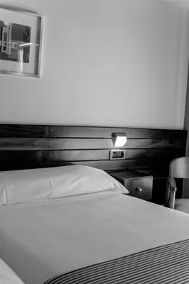 a bedroom with a white bed with a wooden headboard at Hotel Restaurante San Anton in Tapia de Casariego