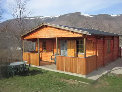 a wooden cabin with a table and chairs in a yard at CABAÑAS LAGO DE SANABRIA in Vigo de Sanabria