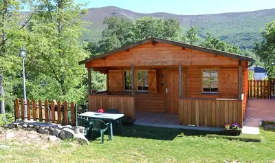 a wooden cabin with a table in front of it at CABAÑAS LAGO DE SANABRIA in Vigo de Sanabria