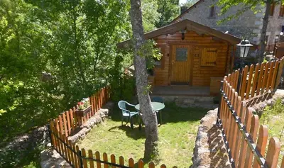a wooden cabin with a table and a fence at CABAÑAS LAGO DE SANABRIA in Vigo de Sanabria