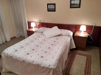 a bedroom with a large bed with two night stands at Hostal Mayo in O Barco de Valdeorras