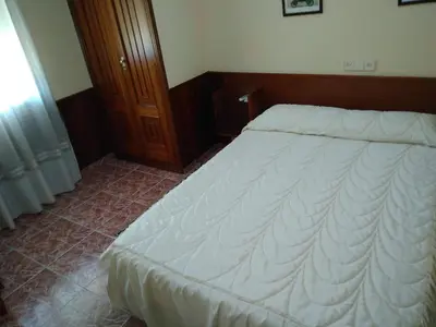 a bedroom with a large bed with white sheets at Hostal Mayo in O Barco de Valdeorras