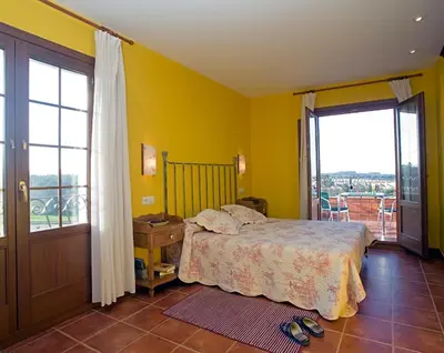 a bedroom with yellow walls and a bed and a balcony at Hotel Rural Suquin in Navia