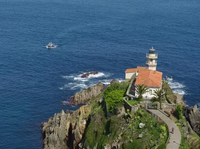 a lighthouse on a cliff next to the ocean at Hotel Rural Suquin in Navia