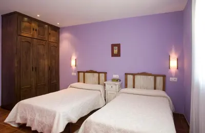 two beds in a room with purple walls at Hotel Rural Suquin in Navia