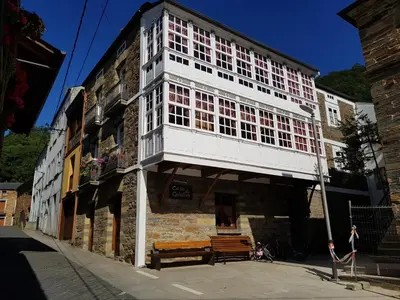a tall white building with a bench on a street at Casa do Catalán - Casa completa - Navia de Suarna in Navia de Suarna