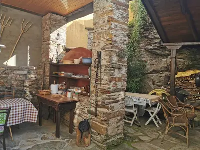 an outdoor kitchen with a table and a stone wall at Casa do Catalán - Casa completa - Navia de Suarna in Navia de Suarna
