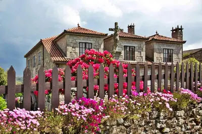 a fence in front of a house with pink flowers at Casa de Cacheiro - Silleda in Silleda