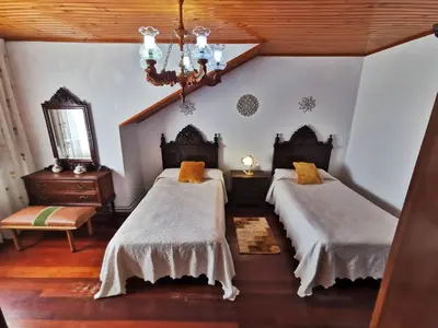 a bedroom with two beds and a chandelier at Casa de Cacheiro - Silleda in Silleda