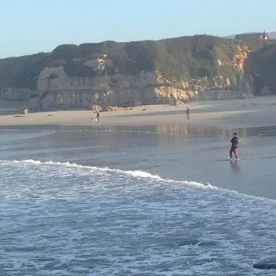 two people are standing in the water on a beach at Costa Reinante Spa in Barreiros