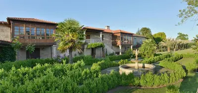 a house with a fountain in the middle of a garden at O Retiro do Conde in Villaza