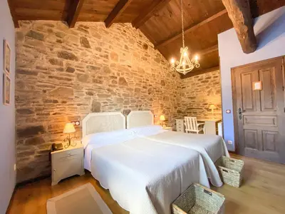 a bedroom with a large white bed in a stone wall at Hotel Casa Cachón in Tol