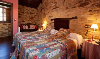 a bedroom with a bed and a stone wall at Hotel Casa Cachón in Tol