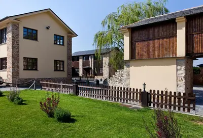 a house with a wooden fence in front of a yard at Hotel Casa Cachón in Tol