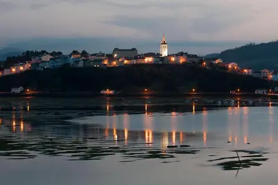 a town on a hill next to the water at night at Hotel Casa Cachón in Tol