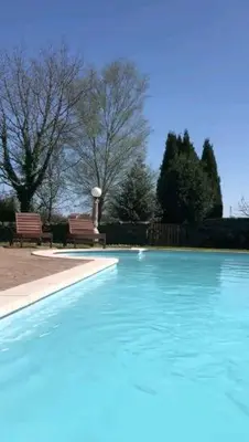a swimming pool with blue water in a park at Casa rural osvilares in Santiago de Compostela