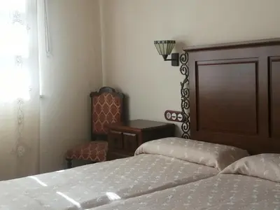 a bedroom with two beds and a chair at Casa rural osvilares in Santiago de Compostela