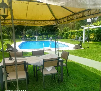 a table and chairs under a yellow umbrella near a swimming pool at Casa Rustica Neiro in Santiago de Compostela
