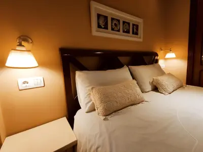 a bedroom with a bed with white pillows and two lights at HHC - Holidays House Compostela in Santiago de Compostela