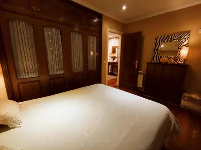 a bedroom with a large white bed and a mirror at HHC - Holidays House Compostela in Santiago de Compostela