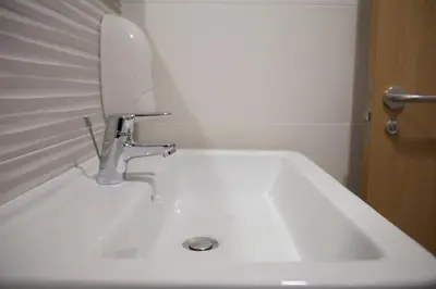 a white bathroom sink with a mirror and a toothbrush at Hostel Cross in Lugo