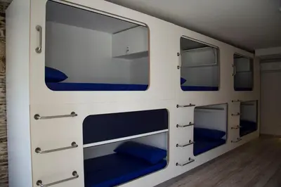a room with four bunk beds with blue cushions at Hostel Cross in Lugo