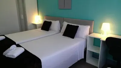 two beds in a small room with two lamps at Pensión Mar Azul in Santiago de Compostela
