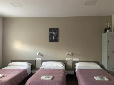 three beds in a room with pink blankets at Albergue Camiño Real in Sigüeiro