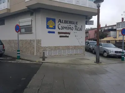 a building with a sign on the side of it at Albergue Camiño Real in Sigüeiro