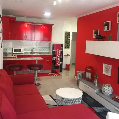 a red living room with a red couch and a kitchen at Apartamento Centro Frente Muralla in Lugo
