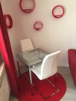 a glass table and two white chairs on a red rug at Apartamento Centro Frente Muralla in Lugo
