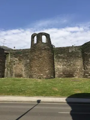 an old brick building with two towers on the side of a road at Apartamento Centro Frente Muralla in Lugo
