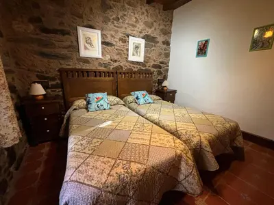 a bedroom with a bed and a stone wall at Eira de Bergondo in Bergondo