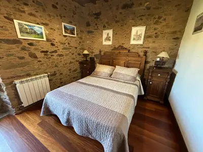 a bedroom with a bed in a room with stone walls at Eira de Bergondo in Bergondo