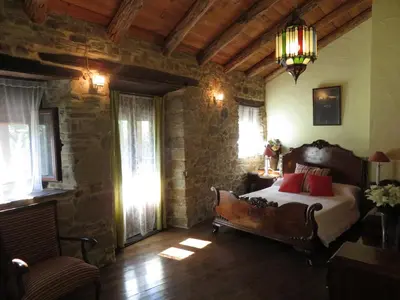 a bedroom with a bed and a chair and windows at Neverending Bierzo in Pobladura de las Regueras