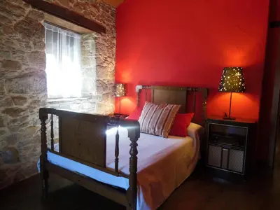 a bedroom with a bed with a red wall at Neverending Bierzo in Pobladura de las Regueras