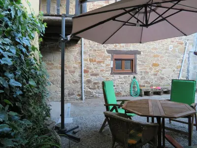 a table and chairs with an umbrella in a courtyard at Neverending Bierzo in Pobladura de las Regueras